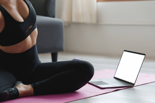 Junge Frau praktiziert Yoga folgen Lehrer in Laptop-Online-Klasse zu Hause. Konzept der Ruhe und Entspannung. - Foto, Bild