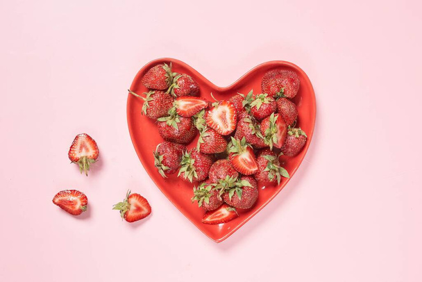 Fresh strawberry fruits on a heart-shaped plate - Foto, afbeelding