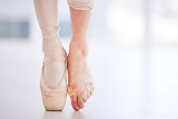 I should definitely tape my feet more often. Cropped shot of a young ballerina wearing a pointe shoe on one foot and band aids on her barefoot. - Foto, Bild