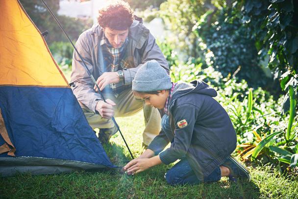 Weekend in the wild with dad. Shot of a father and his young son putting up their tent. - Photo, Image