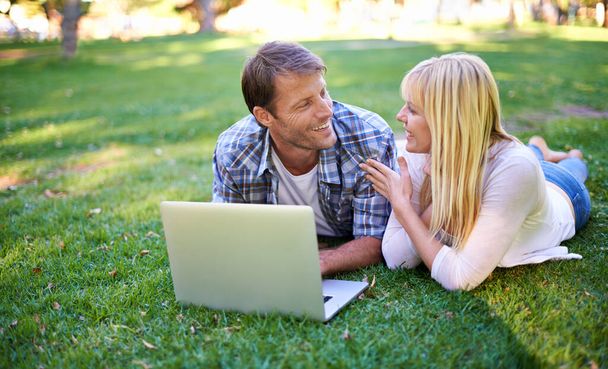 No fair, thats cheating.... Cropped shot of an attractive couple using a laptop outdoors. - 写真・画像