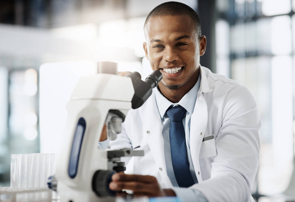 Changing the world one discovery at a time. Cropped portrait of a handsome young male scientist using a microscope while doing research in his lab. - Zdjęcie, obraz