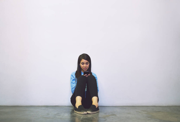 Ze zit tussen de lessen in. Foto van een aantrekkelijke jonge student met behulp van haar mobiele telefoon tijdens het zitten in een campus hal. - Foto, afbeelding
