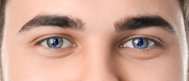 Handsome young man with reflection of bitcoin in his eyes, closeup - Фото, зображення