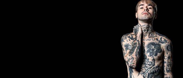 Joven hombre tatuado desnudo sobre fondo negro con espacio para el texto - Foto, imagen