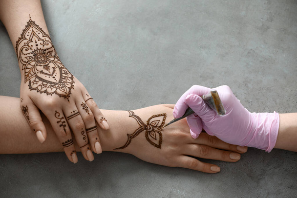 Mehndi-Meister zeichnet Henna-Tätowierung auf weiblicher Hand im Salon - Foto, Bild