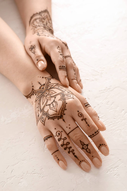 Female hands with beautiful henna tattoo on light background, closeup - Foto, imagen