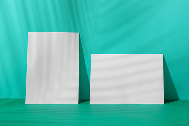 White paper sheets and palm leaf shadow on color background - Fotoğraf, Görsel