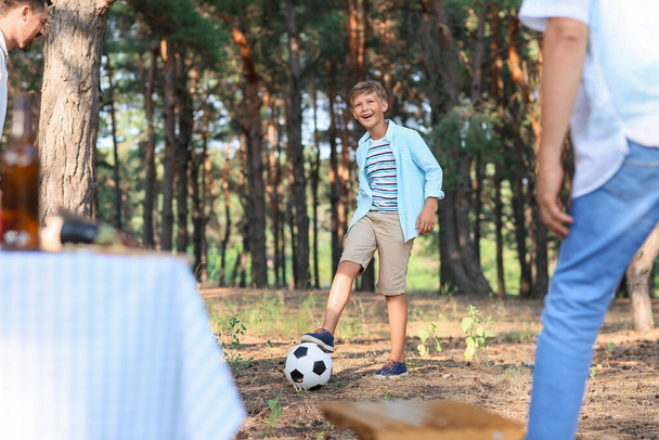 Little boy playing soccer with his father and grandfather in forest - Fotoğraf, Görsel