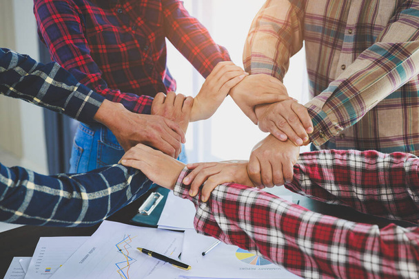 Een diverse groep mensen verbindt hun handen als een ondersteunend teken dat een gevoel van teamwork uitdrukt. Eenheid en samenhorigheid. teamwork tussen bedrijven.  - Foto, afbeelding