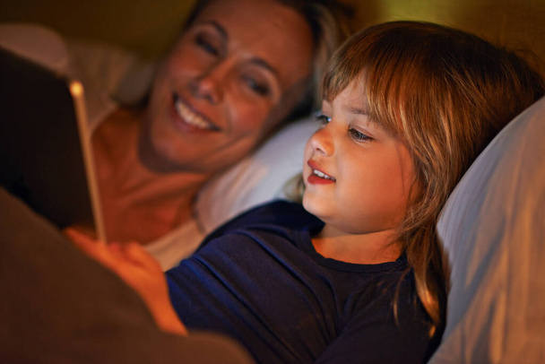 Enjoying time together before bed. A mother and daughter lying in bed with a digital tablet. - Φωτογραφία, εικόνα