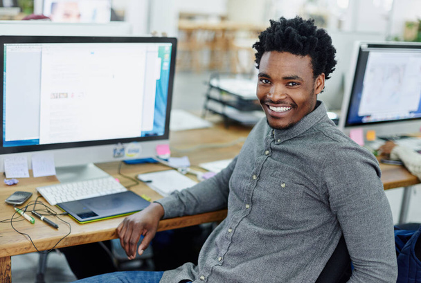 Turning a passion for design into a career. Portrait of an smiling young designer sitting at a computer in an office. - 写真・画像