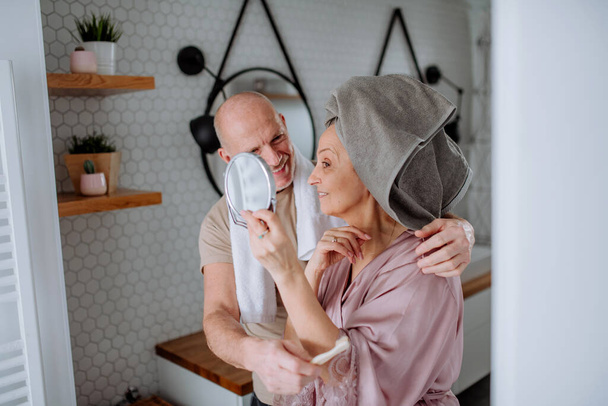 Senior couple in love in bathroom, looking at mirror and smiling, morning routine concept. - Photo, image