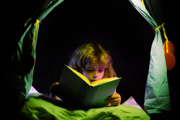 Kids reading books. Dreaming child in kids tent read bedtime stories, fairystory or fairytale. - Foto, imagen