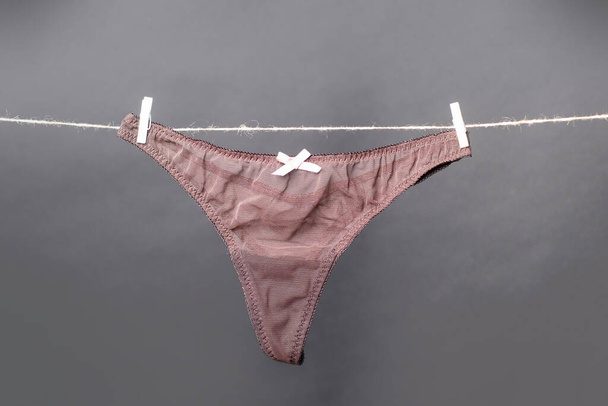 Panties. Female lace lingerie. Womans erotic underwear panties. Womens panties hanging on rope isolated on gray background. - 写真・画像