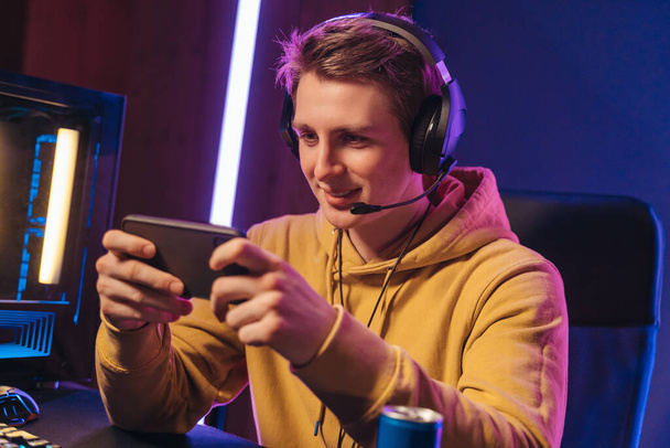 Handsome pro gamer playing mobile video games on online esport tournament - Photo, image