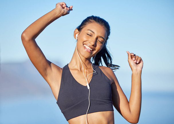 Music lifts my mood in an instant. Shot of a sporty young woman listening to music while exercising outdoors. - Foto, Bild