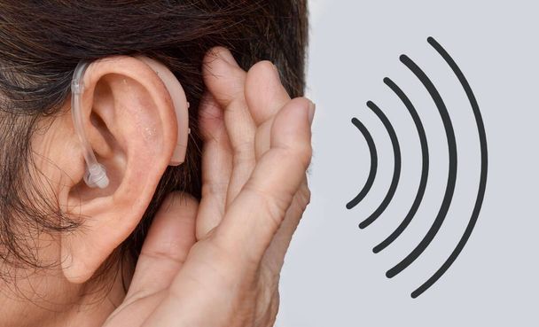 Apparecchio acustico elettronico nell'orecchio della vecchia asiatica con sordità totale. - Foto, immagini