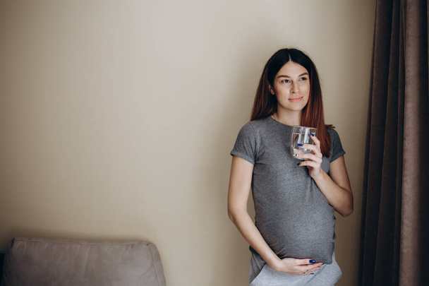 Young pregnant woman drinking water - Foto, afbeelding