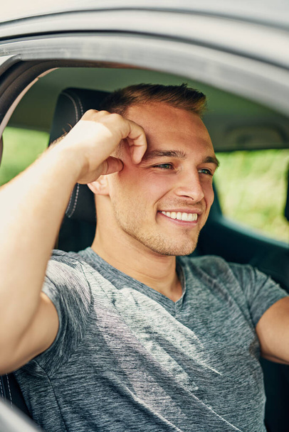 He enjoys the freedom of being on the road. Shot of a young man driving a car. - Foto, Bild