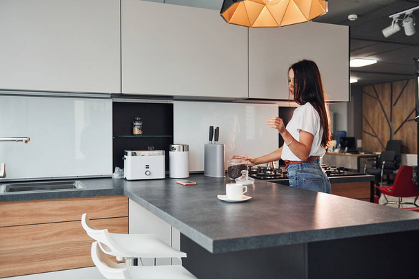 Young beautiful brunette in casual clothes preparing coffee in kitchen at daytime. - Foto, Bild