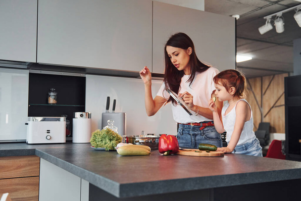 Mother teaching her little daughter preparing food indoors in kitchen. - Foto, immagini