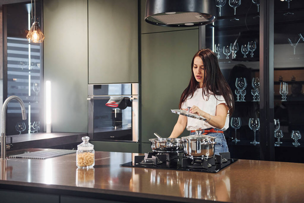 Preparing fresh food. Young beautiful brunette in casual clothes indoors in kitchen at daytime. - Фото, зображення