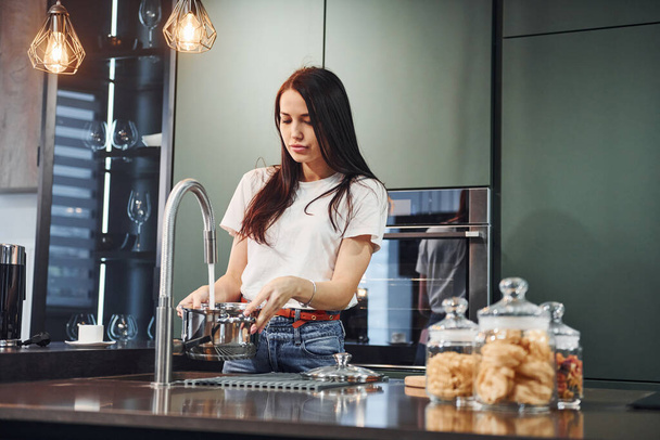Preparing fresh food. Young beautiful brunette in casual clothes indoors in kitchen at daytime. - Foto, Imagem