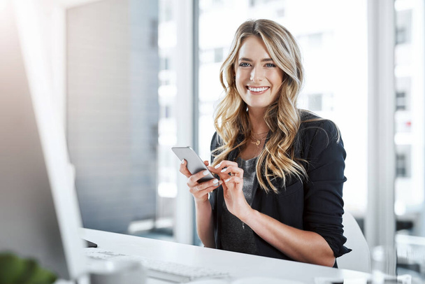 Produktivität durch Technologie. Aufnahme einer jungen Geschäftsfrau mit einem Mobiltelefon an ihrem Schreibtisch in einem modernen Büro. - Foto, Bild
