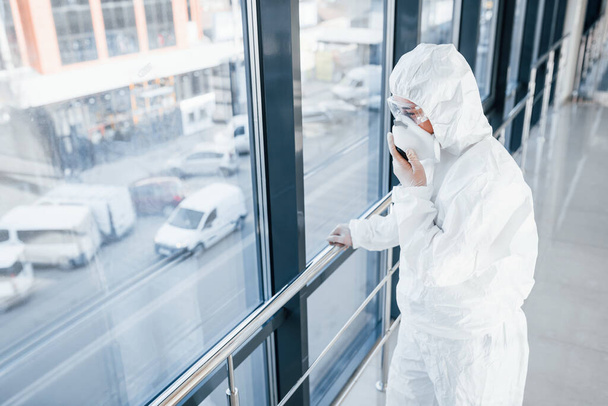 Female doctor scientist in lab coat, defensive eyewear and mask standing indoors. - Fotó, kép