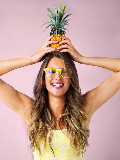 Будь как ананас, всегда носи корону. Студийный снимок молодой женщины, держащей ананас на розовом фоне. - Фото, изображение