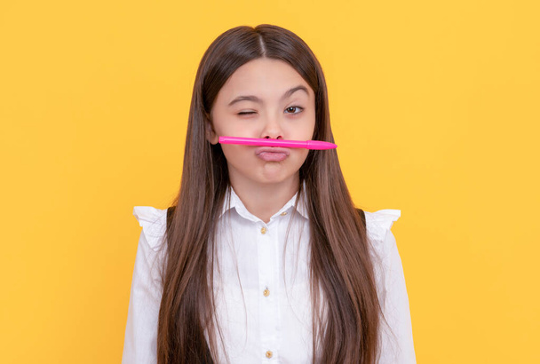 Playful winking girl child hold pen as mustache yellow background, school - Zdjęcie, obraz