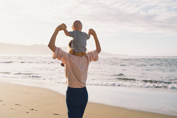 Mother with small child playing and having fun together on beach ocean. Happy family outdoors. Mom and baby at summer on nature. Positive human emotions and feelings. Family holiday on sea coast. - Foto, Imagem