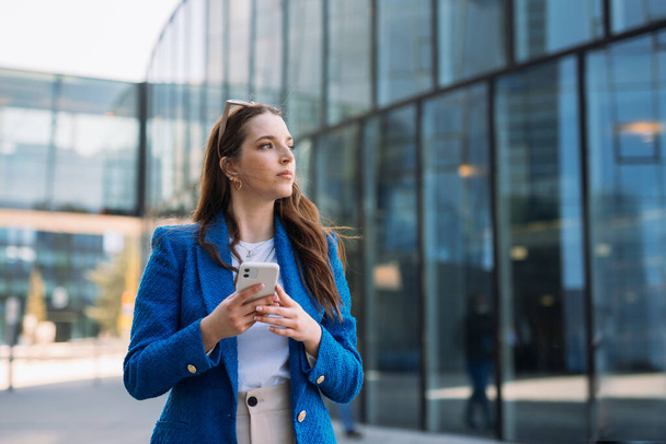 Mujer de negocios moderna en traje azul usando teléfono móvil. Mirando hacia otro lado. Espacio de copia - Foto, Imagen