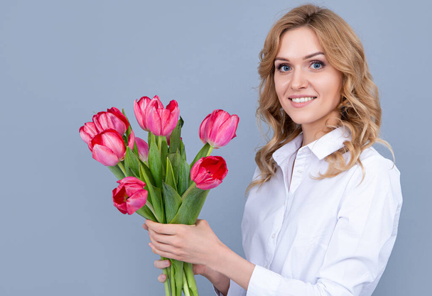 face of happy young woman with spring tulip flowers on grey background - Фото, изображение