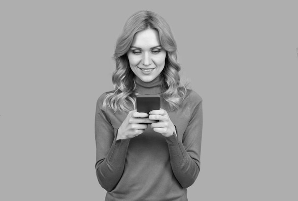Hübsche Frau SMS-Kurznachricht auf Handy-Gerät grauen Hintergrund, SMS - Foto, Bild