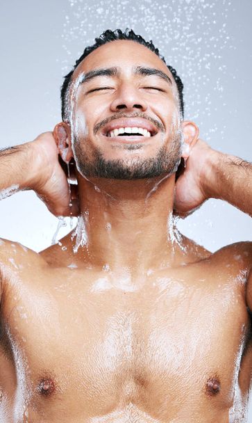I always feel rejuvenated after a shower. Studio shot of a handsome young man taking a shower against a grey background. - 写真・画像