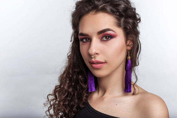 Elegant and gental pretty young woman with professional makeup curly volume hairstyle and nose and ears piercing - Zdjęcie, obraz