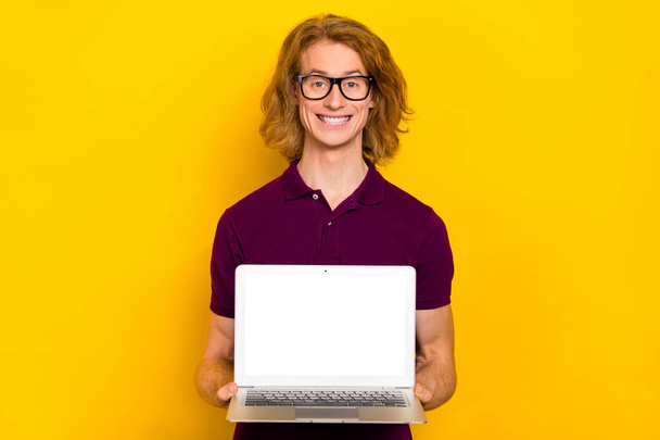 Photo of cute millennial red hairdo guy show laptop wear eyewear purple polo isolated on yellow color background - Foto, Imagem