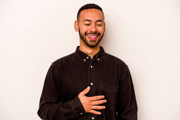Nuori latino mies eristetty valkoisella taustalla koskettaa vatsa, hymyilee varovasti, syöminen ja tyytyväisyys käsite. - Valokuva, kuva