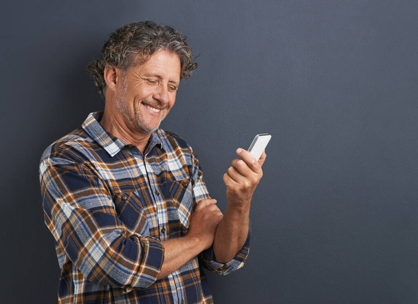 Who said old dogs cant learn new tricks. A cropped shot of a happy mature man using his smartphone. - Zdjęcie, obraz