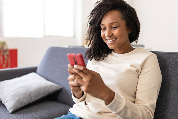 Змішана раса молода жінка використовує смартфон вдома
 - Фото, зображення