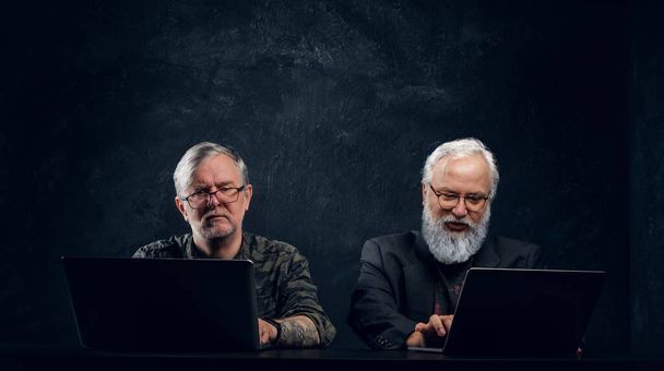 Team of two contemporary elderly men against dark background - Foto, imagen