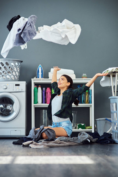 Świeżość to wolność. Całkowite ujęcie atrakcyjnej młodej kobiety wyrzucającej pranie w powietrze podczas robienia prania w domu. - Zdjęcie, obraz