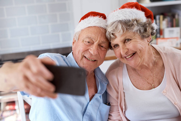 Prends déjà la photo. Prise de vue d'un couple âgé prenant un selfie festif à la maison. - Photo, image