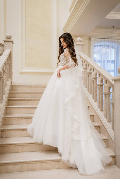 Charming happy bride with long veil. marble staircase - Foto, imagen