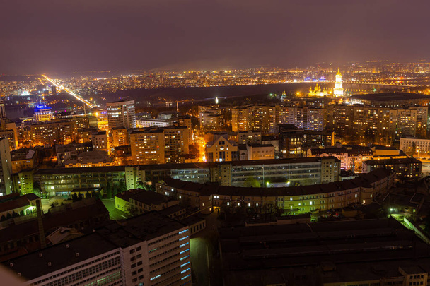 Ukraine, Kyiv  March 12, 2016: Aerial panoramic view on central part of Kyiv city from a roof of a high-rise building. Night life in a big city. Foggy and rainy weather.  - 写真・画像