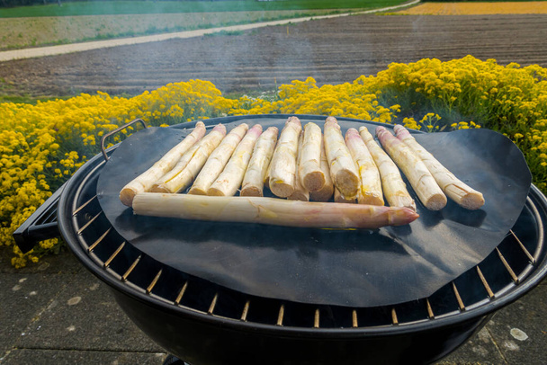 Preparation of asparagus on a small coal round grill - Foto, afbeelding