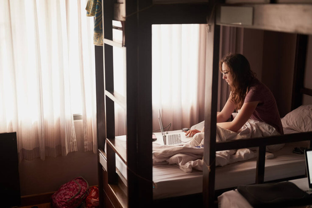 Whats on the itinerary for today. Shot of a young woman using a laptop while sitting in bed. - Foto, imagen