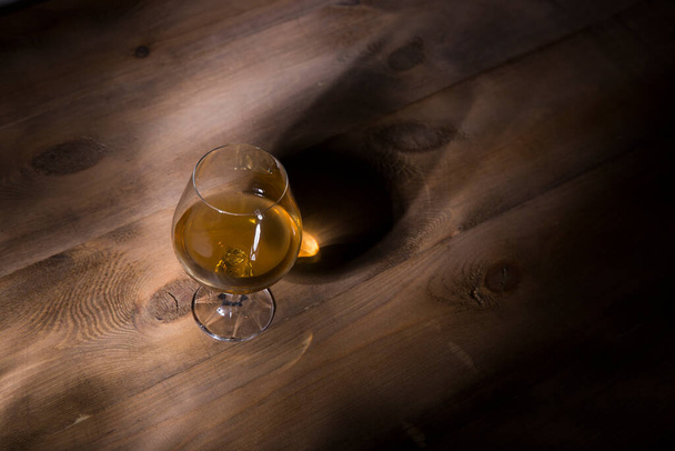 Glass of brandy or cognac on the wooden table - 写真・画像
